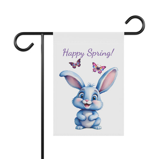 White garden flag displayed on a black metal pole, featuring a cute blue cartoon bunny rabbit with a happy expression, two colorful butterflies, and the text "Happy Spring!" in purple script.