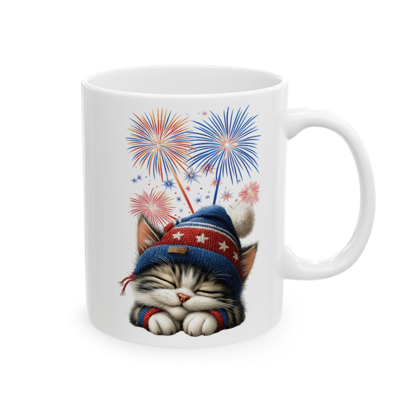 White ceramic coffee mug with a sleepy kitten wearing a patriotic hat and surrounded by red, white, and blue fireworks.