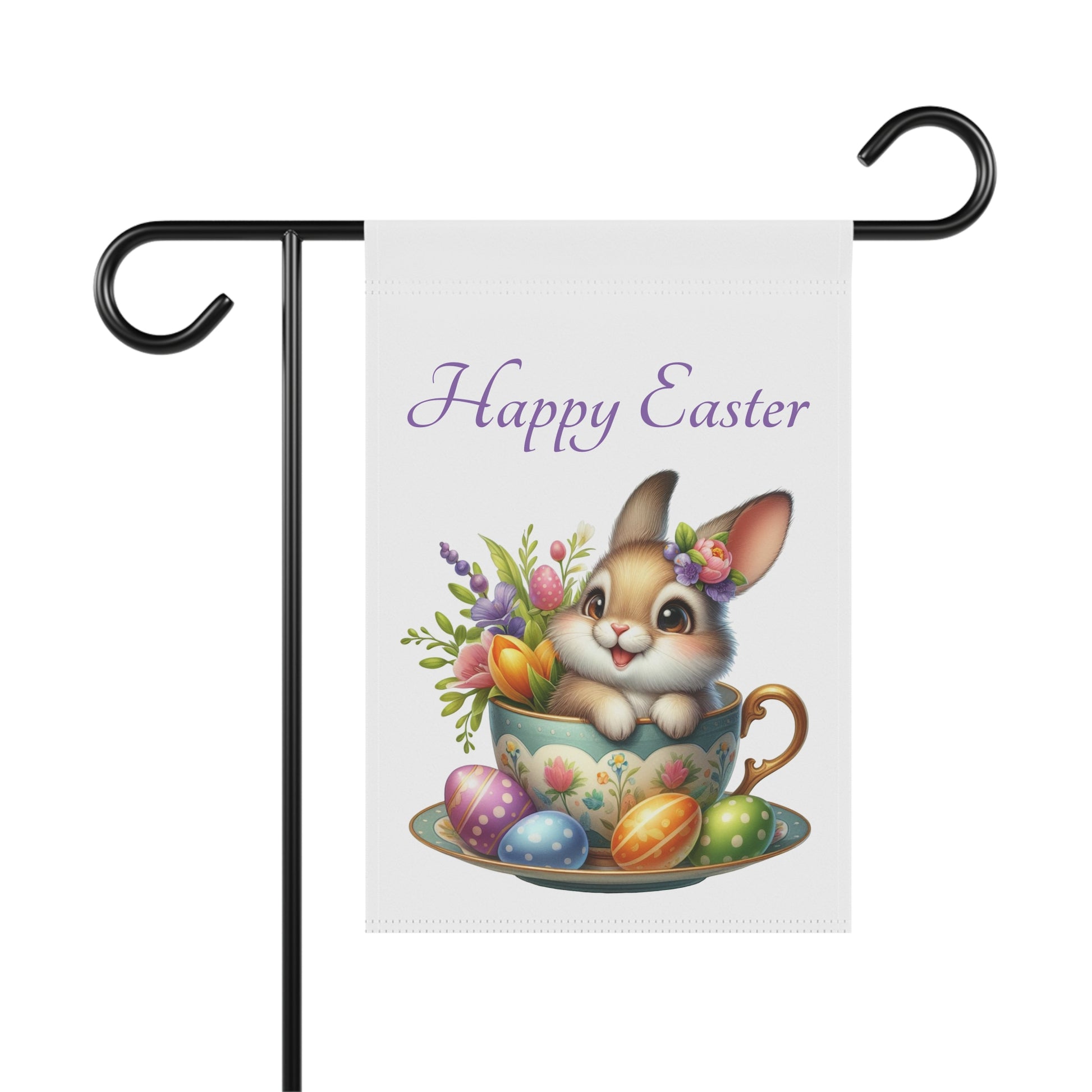 White garden flag with "Happy Easter" in purple text, featuring a cute brown cartoon bunny with a flower crown sitting in a floral patterned teacup, surrounded by colorful Easter eggs and spring flowers. The flag is displayed on a black metal garden flag stand.