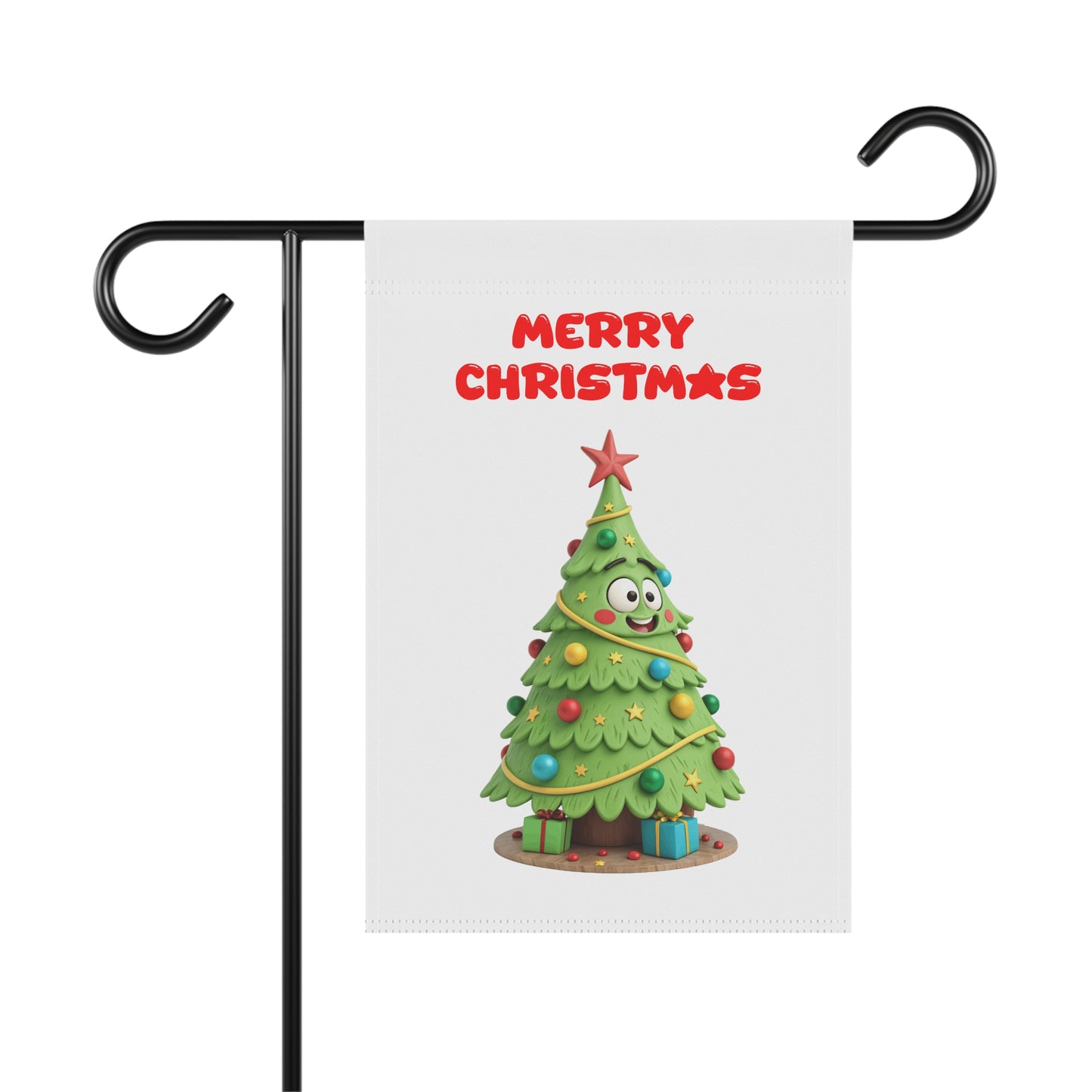 A white garden flag with a funny 3D-style illustration of a happy cartoon Christmas tree with googly eyes, decorated with colorful ornaments and presents, with "Merry Christmas" in red text above it. The flag is shown hanging from a black metal garden flag stand.