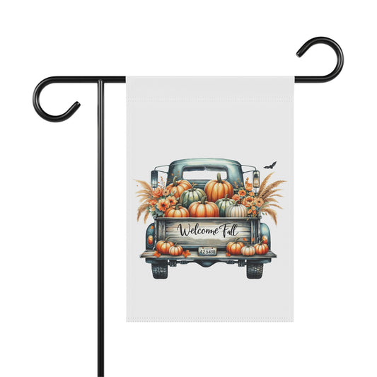 White garden flag with a vintage teal pickup truck loaded with various orange and green pumpkins, fall flowers, and wheat stalks, with "Welcome Fall" written on the tailgate. A small bird flies above.
