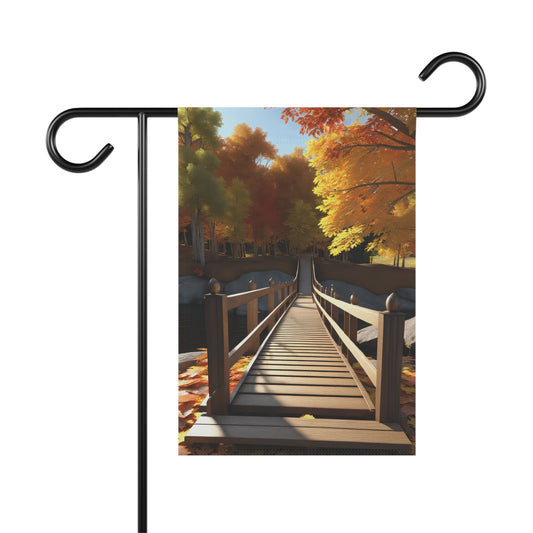 Garden flag depicting a scenic autumn landscape with a wooden footbridge over water, surrounded by trees with colorful red, orange, and yellow fall leaves, and fallen leaves on the ground.