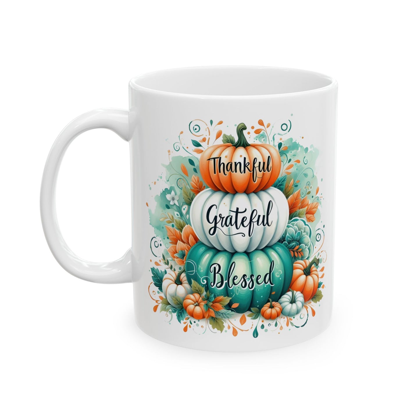 White ceramic coffee mug with a watercolor illustration of three stacked pumpkins (orange, white, teal) with the words "Thankful Grateful Blessed" written on them, surrounded by fall leaves and small pumpkins.