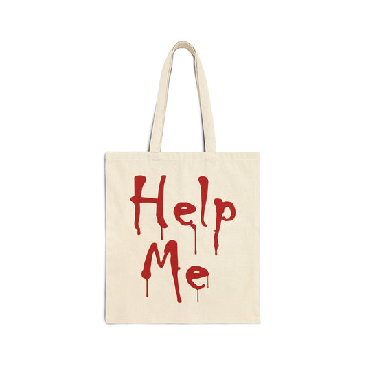 A cream-colored canvas tote bag featuring the words "Help Me" written in a bold, dripping red font that resembles blood.