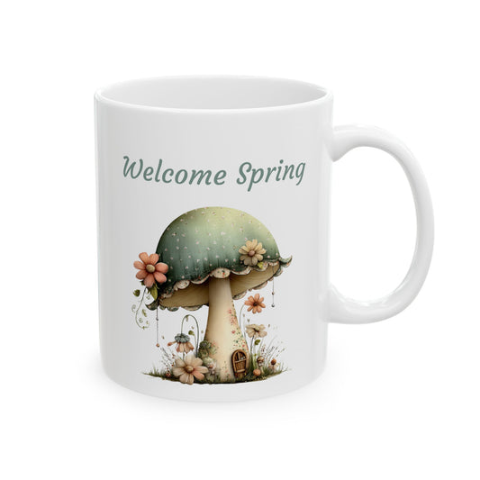 White ceramic coffee mug printed with sage green Welcome Spring text above a whimsical sage green mushroom house with a tiny door and flowers