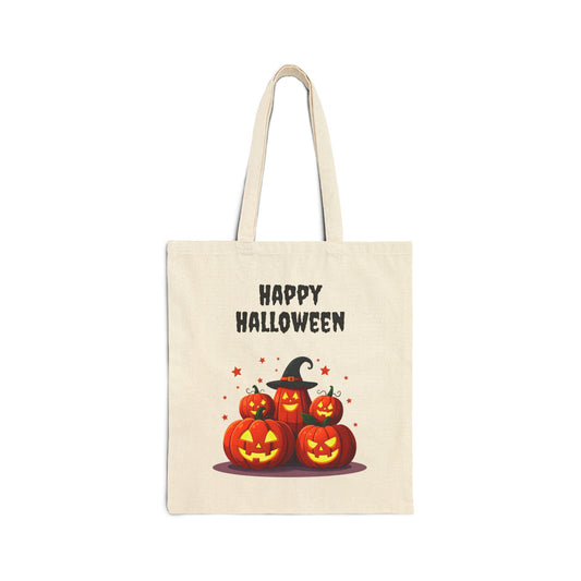 A cream-colored 100% cotton canvas tote bag featuring an illustration of a festive stack of jack-o'-lanterns with one wearing a witch hat. The text "HAPPY HALLOWEEN" is printed above them.