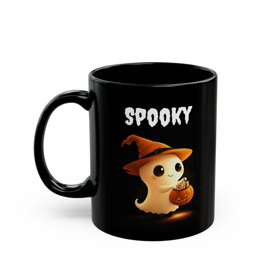 Black ceramic coffee mug with a glowing white cartoon ghost wearing an orange witch hat, holding a small jack-o'-lantern pumpkin filled with candy, and white text above it that reads 'SPOOKY'
