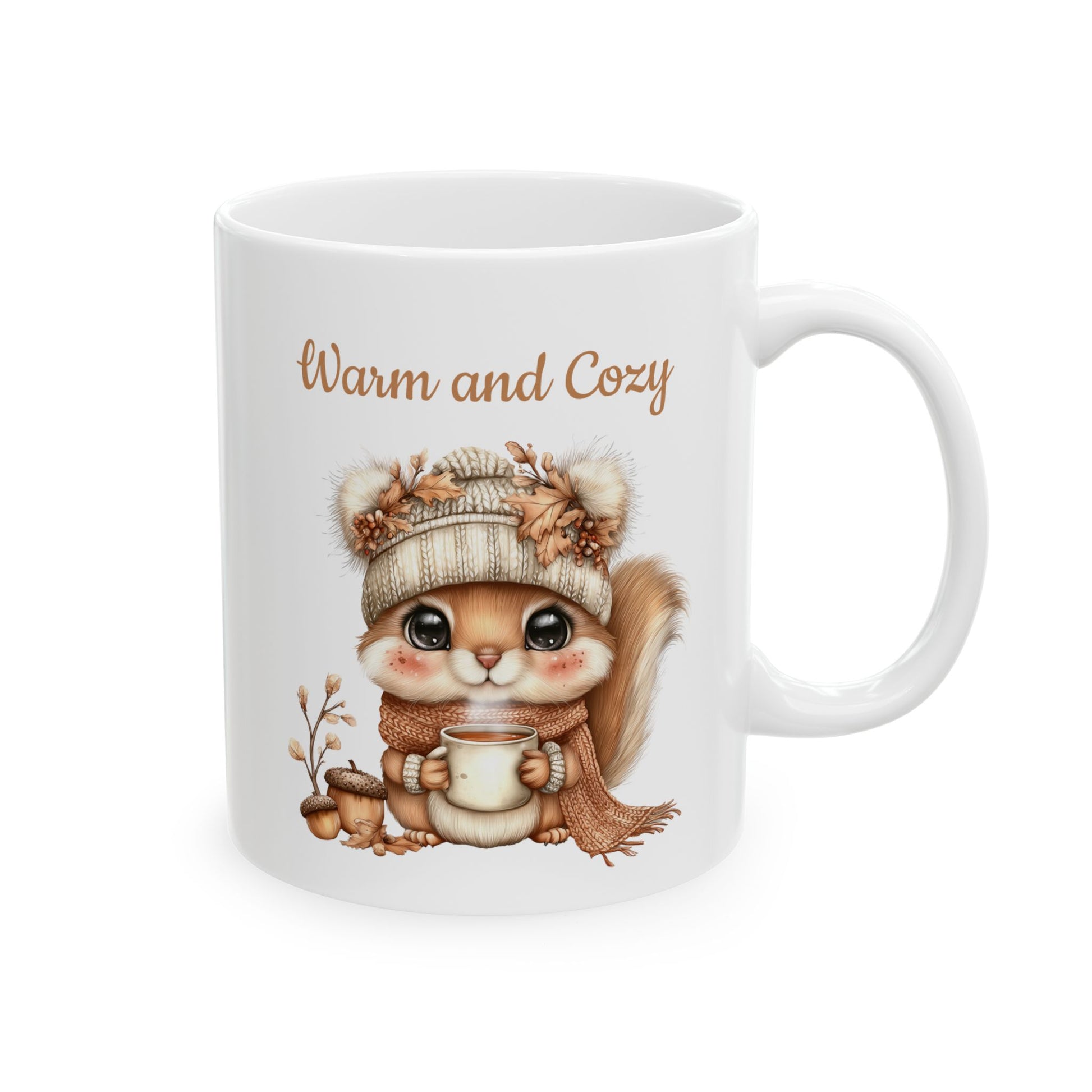 Warm and Cozy ceramic coffee mug featuring a cute illustration of a baby squirrel wearing a knit winter hat and scarf while holding a steaming mug next to acorns and autumn details.