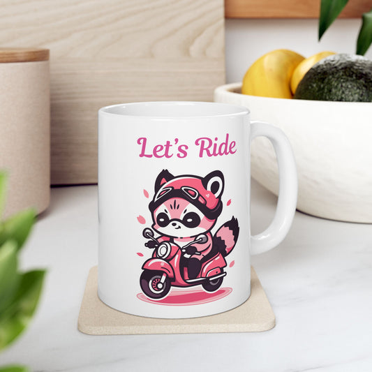 White ceramic coffee mug with a pink cartoon raccoon wearing a helmet and riding a pink scooter, with the text "Let's Ride" above it.