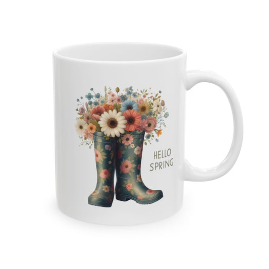 White ceramic coffee mug with a "Hello Spring" design of floral rain boots filled with a bouquet of wildflowers.

