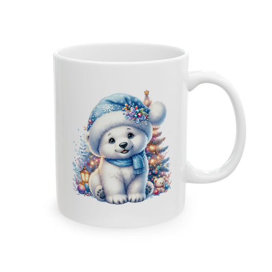 White ceramic coffee mug printed with an illustration of a cute white polar bear cub in a blue plush Santa hat sitting in front of a glowing lit Christmas tree