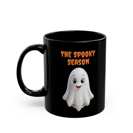 Black ceramic coffee mug with a cute white cartoon ghost smiling, and orange text above it that reads 'THE SPOOKY SEASON
