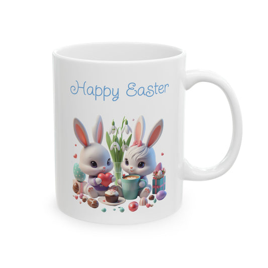 White ceramic coffee mug with a cute illustration of two cartoon bunnies, one holding a heart and one with a pink bow, surrounded by Easter eggs, a cupcake, and chocolates, with the words "Happy Easter" in blue script text above them.

