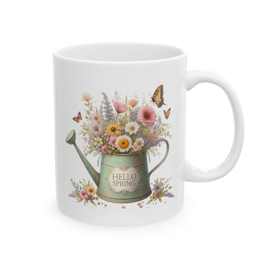 Front view of a white ceramic coffee mug with a vintage mint green watering can full of wildflowers and the text "HELLO SPRING."