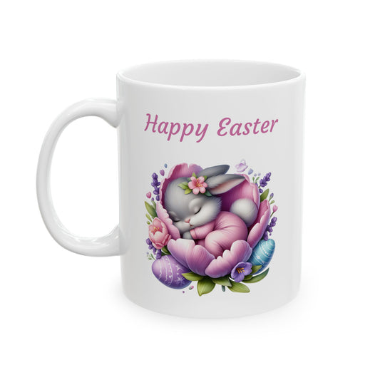White ceramic mug with "Happy Easter" text in pink, featuring a cute grey baby bunny sleeping peacefully inside a large purple and pink flower, surrounded by smaller flowers and two decorated Easter eggs.

