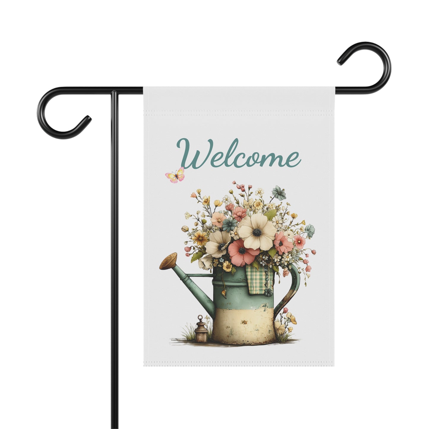Garden flag on a black metal stand printed with teal script Welcome text above a vintage watering can overflowing with wildflowers and a small butterfly
