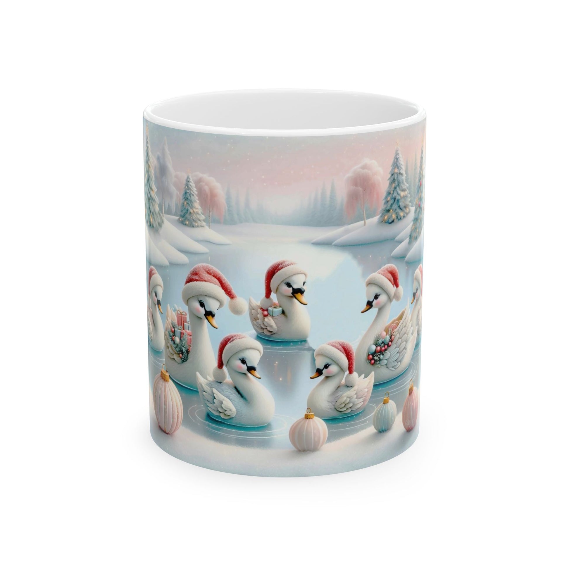 White ceramic coffee mug with a beautiful illustration of several white swans and cygnets, all wearing red Santa hats, swimming in a frozen pond surrounded by a snowy winter landscape with trees and decorative pink globes.

