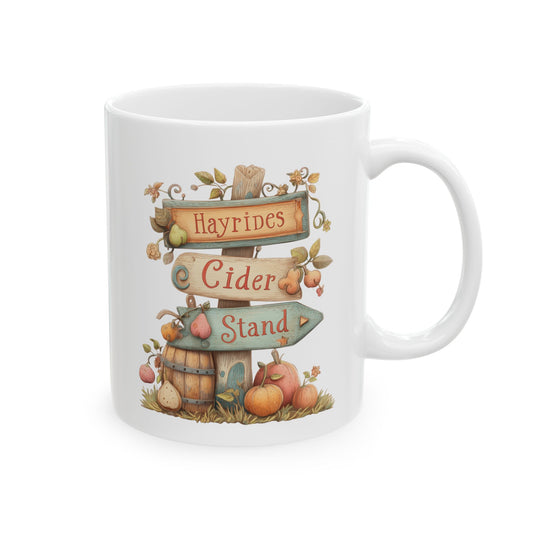 White ceramic coffee mug featuring a soft watercolor illustration of a rustic wooden signpost reading Hayrides Cider Stand, surrounded by apples, a barrel, and pumpkins.
