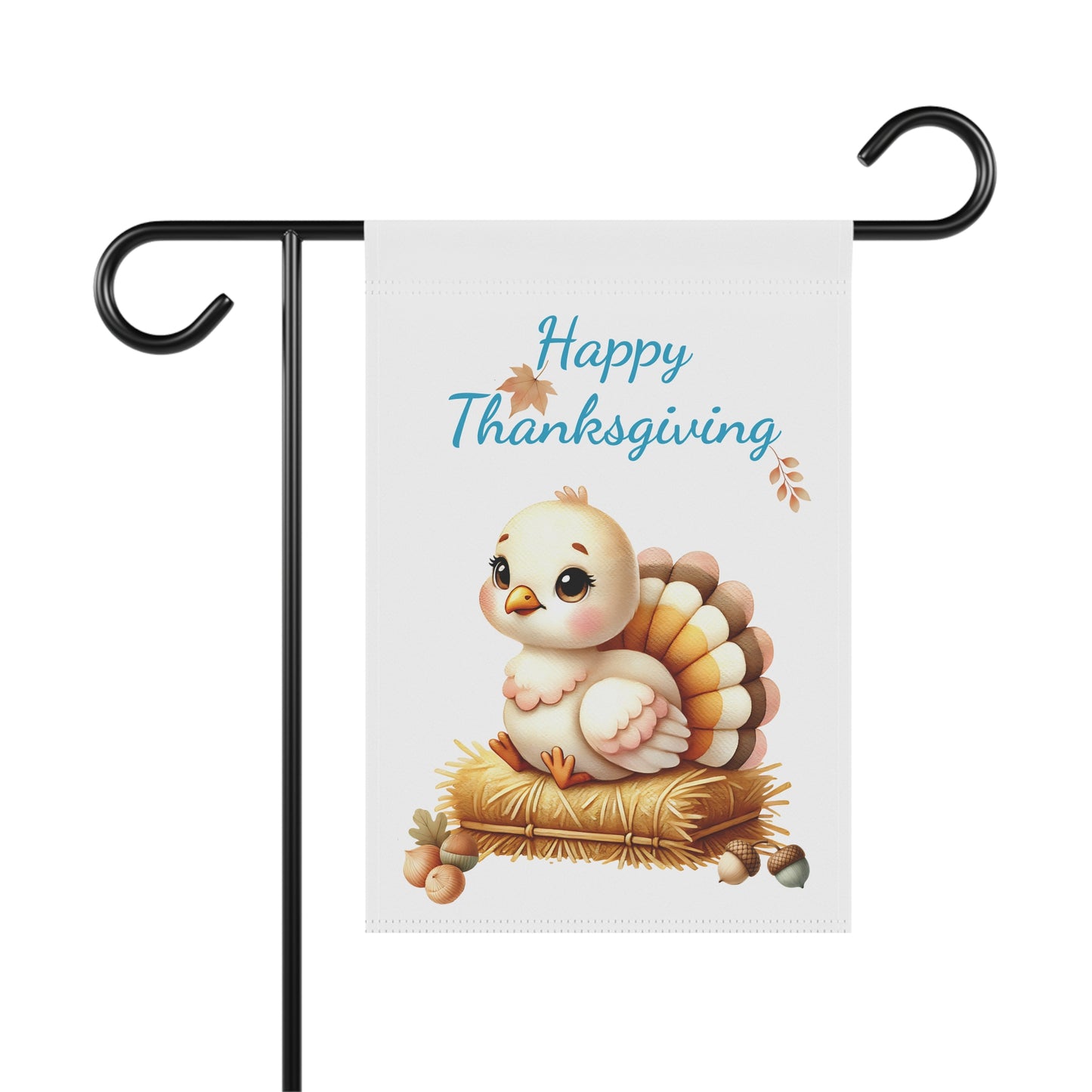 A white vertical garden flag displayed on a black metal flag stand. The flag features the text 'Happy Thanksgiving' in blue script with small brown leaves, positioned at the top. Below the text is an illustration of a cute, plump baby turkey with a light body and layered brown and orange tail feathers, sitting on a pile of yellow hay or straw. Small autumn leaves and acorns are scattered around the hay. 