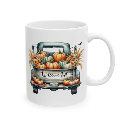 White ceramic coffee mug with a watercolor illustration of the back of a vintage teal pickup truck filled with pumpkins, gourds, and fall foliage, with "Welcome Fall" written on the tailgate.