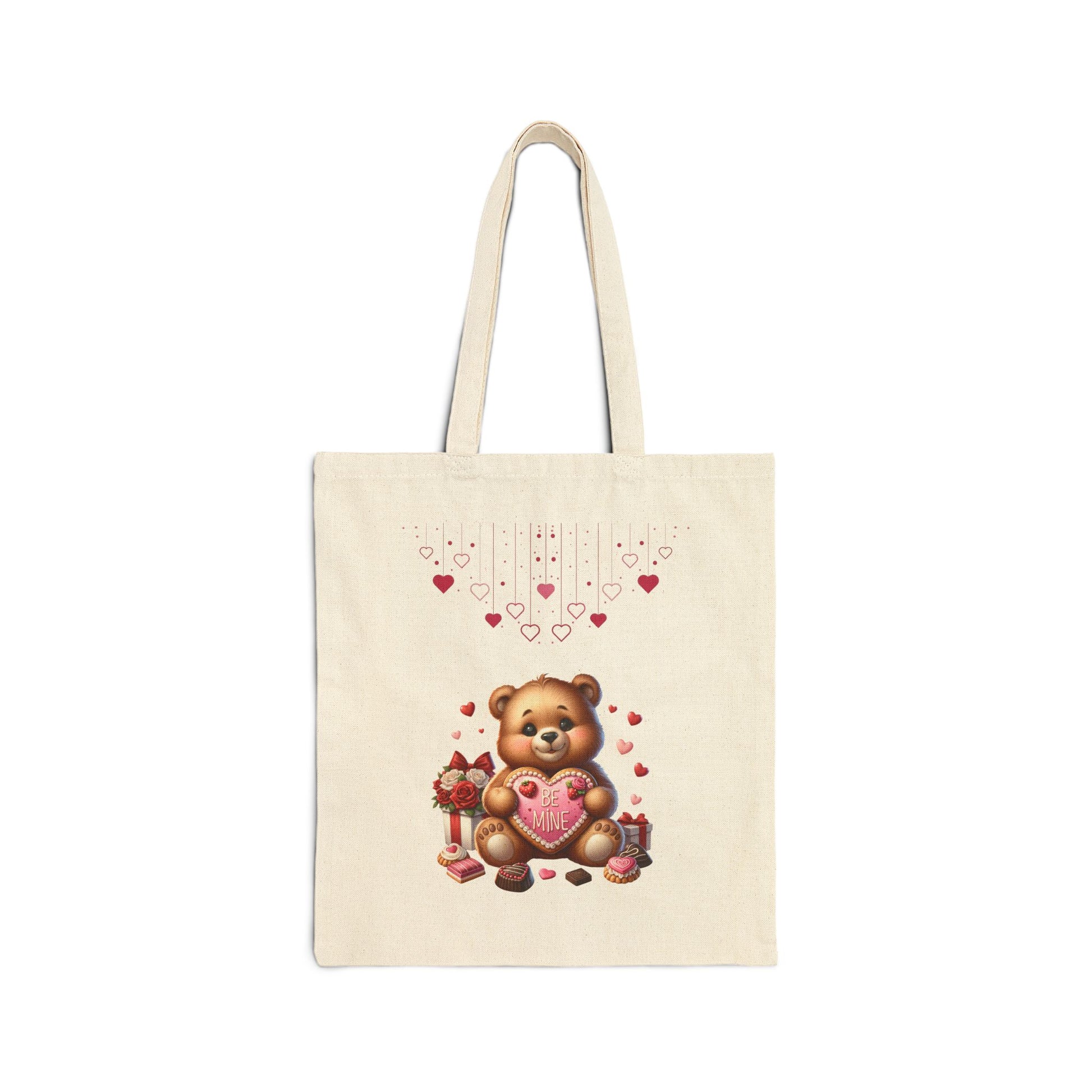 A natural canvas tote bag featuring a cute teddy bear holding a "BE MINE" heart, with small hearts floating above.
