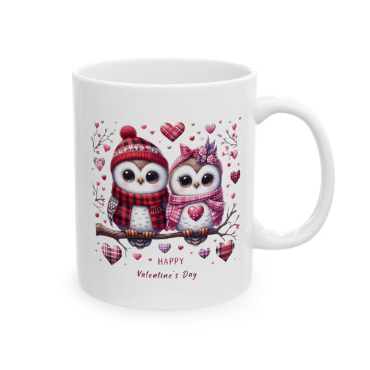 White ceramic coffee mug with a charming illustration of two cartoon owls wearing winter hats and scarves, sitting on a branch surrounded by hearts, and the text "Happy Valentine's Day."

