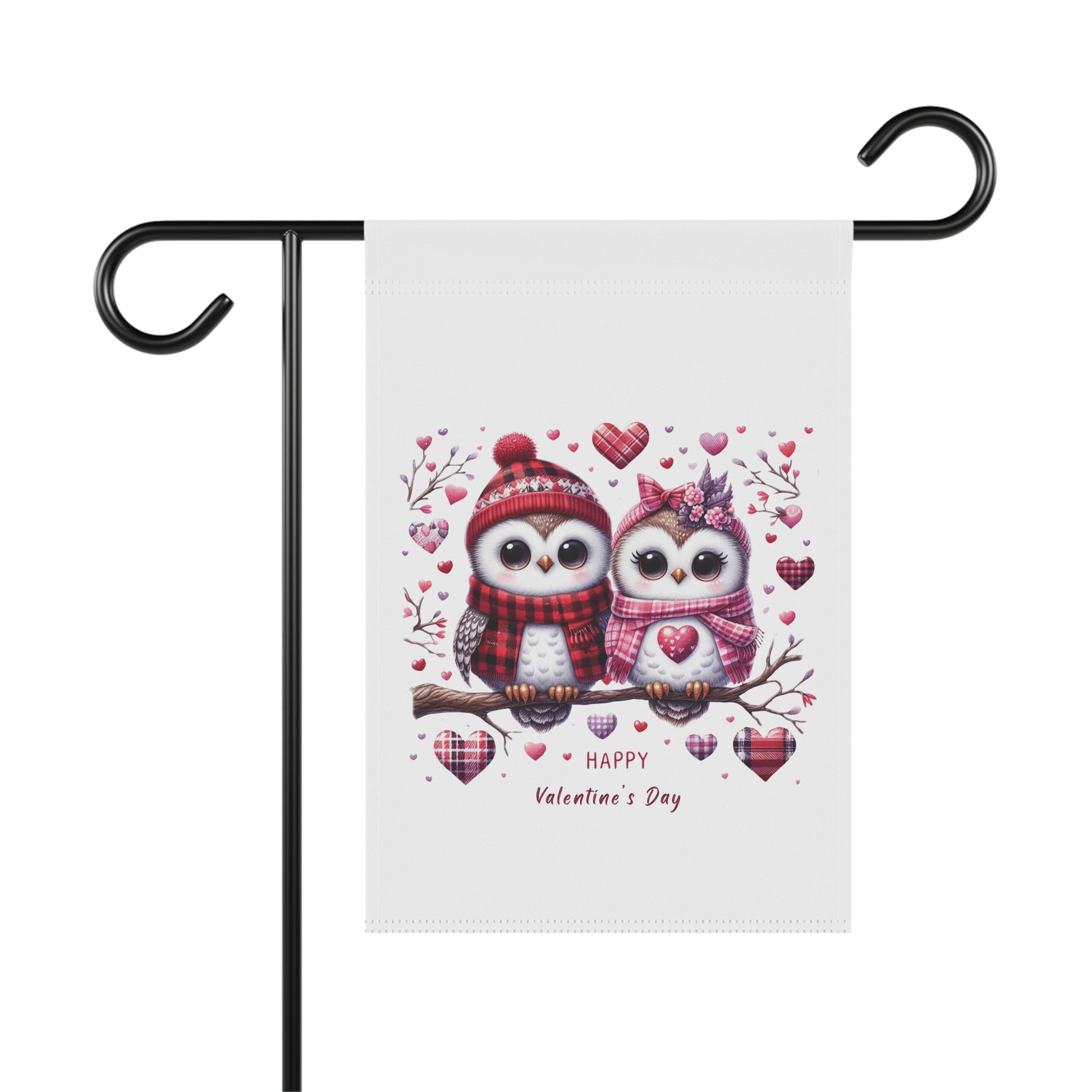 Happy Valentine's Day garden flag with a charming illustration of two cartoon owls wearing winter hats and scarves, sitting on a branch surrounded by hearts. The flag is hanging on a black metal holder.

