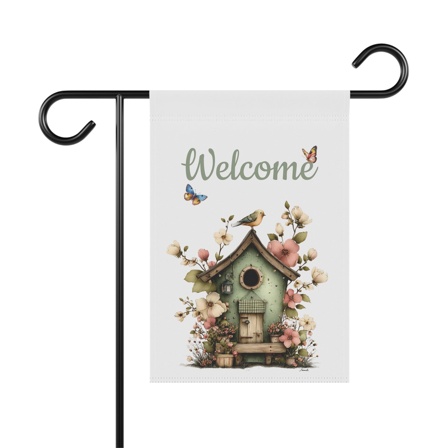 Garden flag on a black metal stand printed with green script Welcome text above a rustic sage green birdhouse framed by garden flowers and butterflies