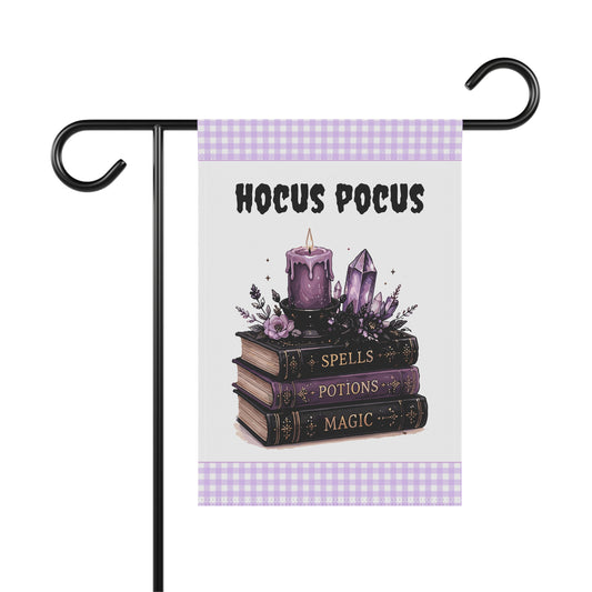 Whimsical Halloween garden flag featuring a stack of vintage magical books labeled Spells, Potions, and Magic, topped with a purple candle and amethyst crystal cluster beneath the black text Hocus Pocus, with purple gingham borders.

