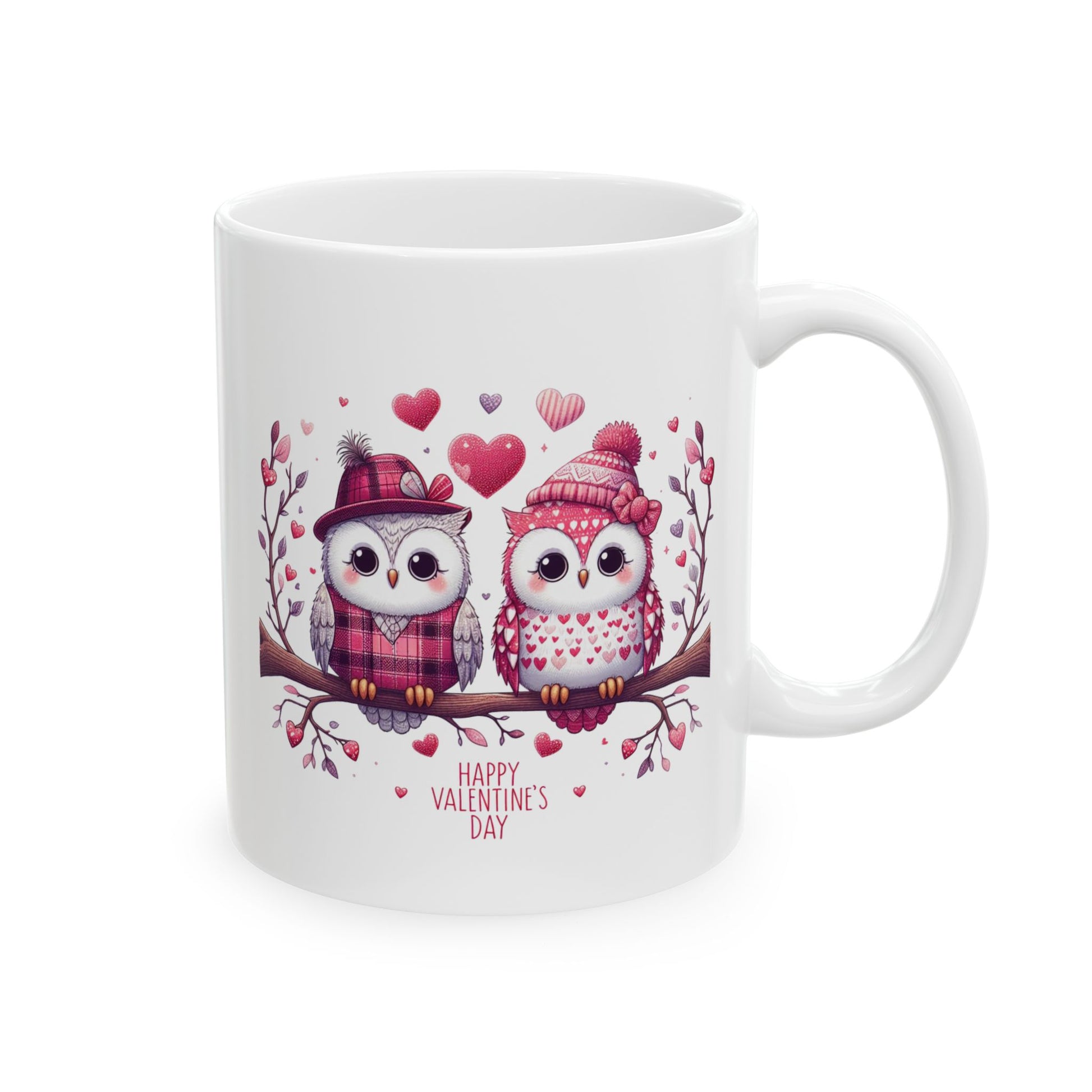 White ceramic coffee mug with a charming illustration of two cartoon owls wearing winter hats and scarves, sitting on a branch surrounded by hearts, and the text "Happy Valentine's Day."

