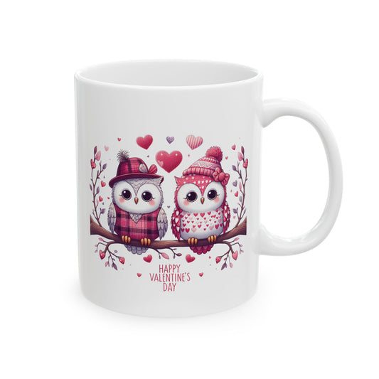 White ceramic coffee mug with a charming illustration of two cartoon owls wearing winter hats and scarves, sitting on a branch surrounded by hearts, and the text "Happy Valentine's Day."

