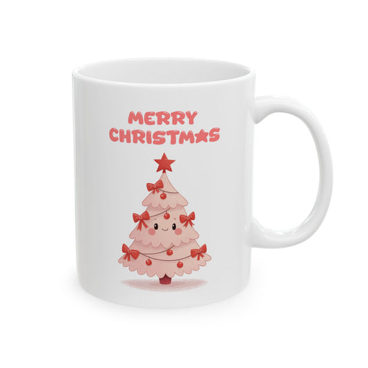 White ceramic coffee mug with a cute, smiling pink Christmas tree illustration, decorated with red bows and a star, and the words "Merry Christmas" in pink bubble letters above it.

