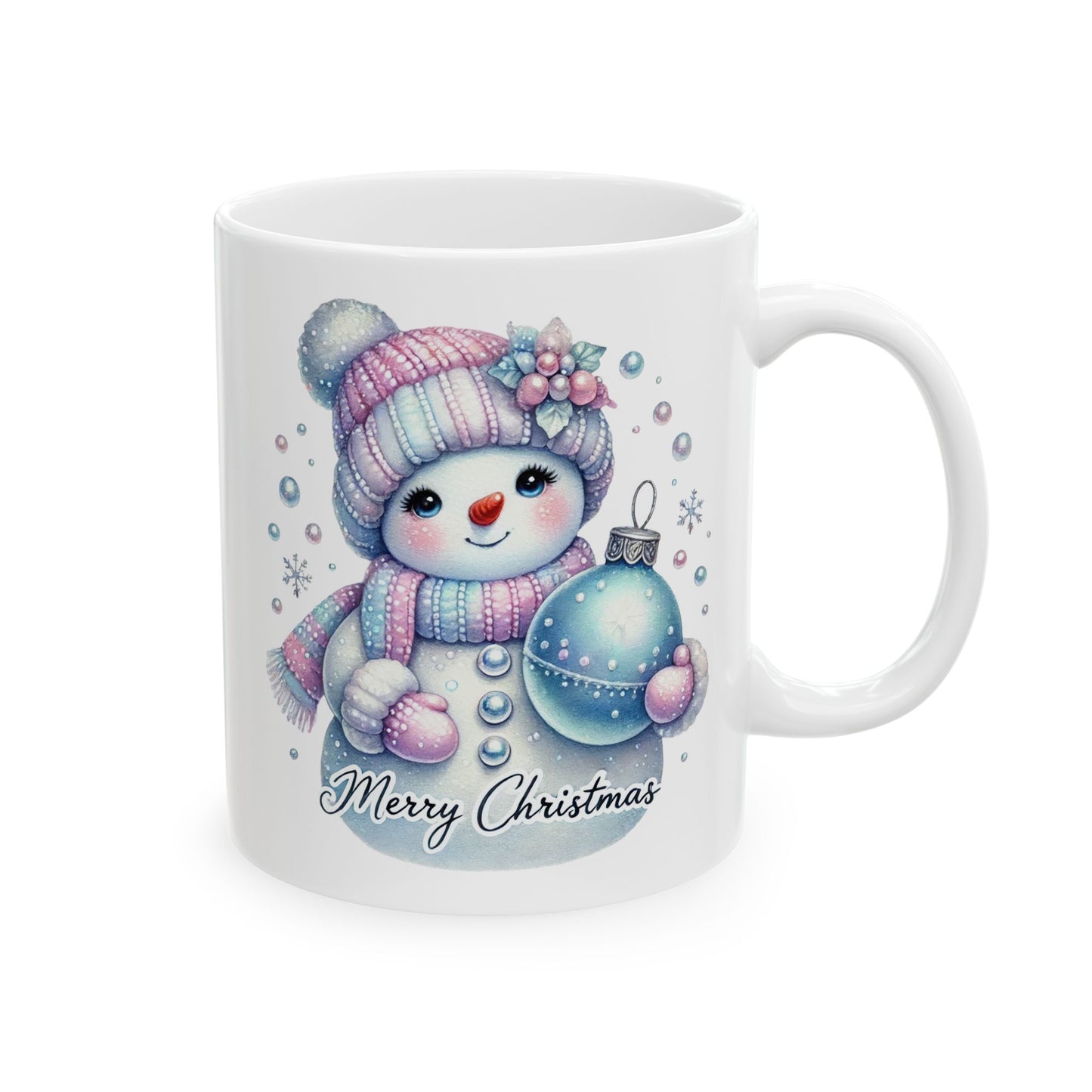 White ceramic coffee mug with a watercolor illustration of a cute snowman wearing a pink and blue striped hat and scarf, holding a blue Christmas ornament, with "Merry Christmas" written below.
