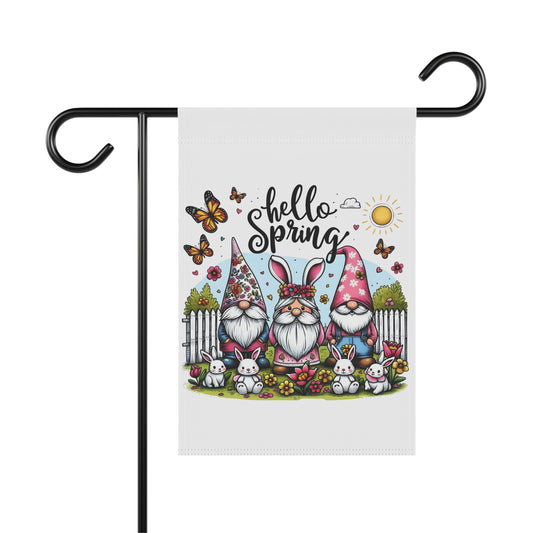 Spring garden flag featuring three whimsical garden gnomes wearing tall hats and bunny ears, surrounded by little white rabbits, butterflies, and spring flowers under text reading Hello Spring.