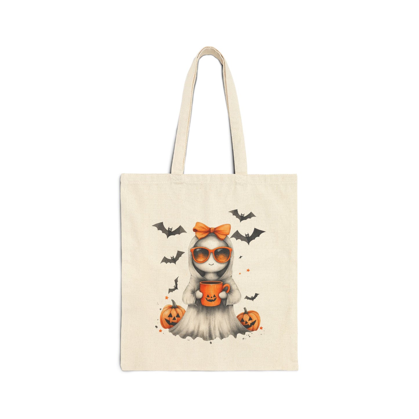 A cream-colored canvas tote bag featuring a cute ghost illustration wearing orange sunglasses and an orange bow, holding a pumpkin mug. Bats are flying in the background, and pumpkins are on the ground.