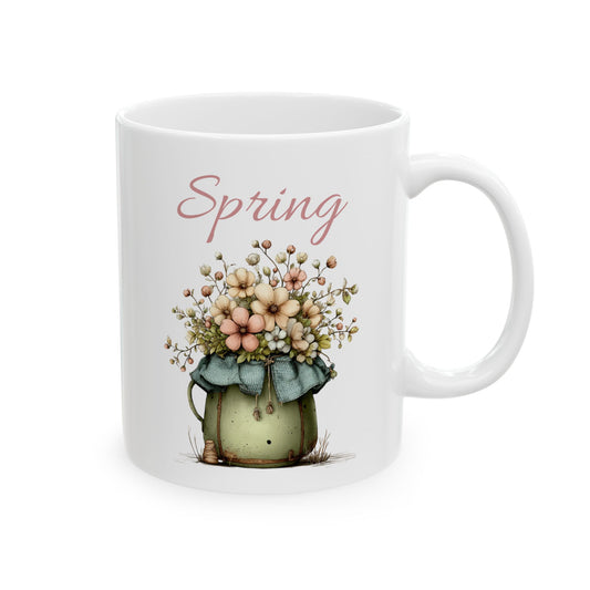 White ceramic coffee mug printed with dusty pink Spring text above a charming green pot brimming with pastel wildflowers