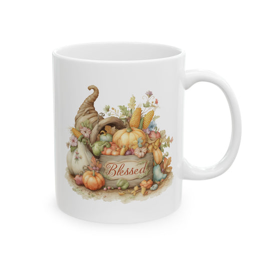 White ceramic coffee mug printed with red Blessed script over a rustic wooden crate filled with a cornucopia, pumpkins, and autumn harvest vegetables