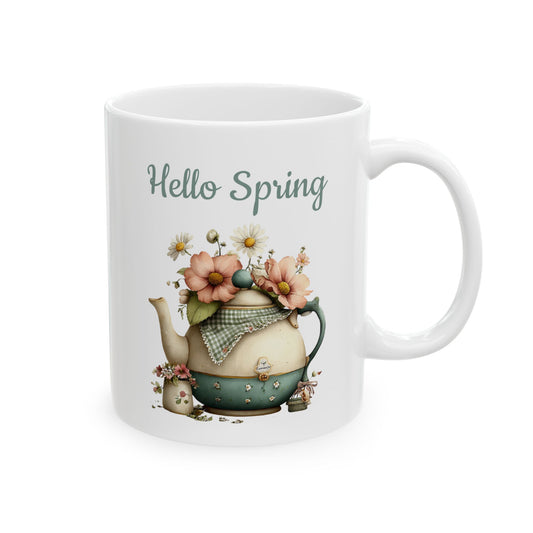White ceramic coffee mug printed with sage green Hello Spring text above a vintage teapot overflowing with soft spring flowers