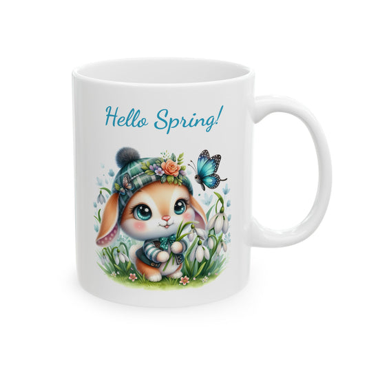 Front view of a white ceramic coffee mug with a cute, big-eyed cartoon bunny wearing a plaid beanie in a field of snowdrop flowers, with the text "Hello Spring!".