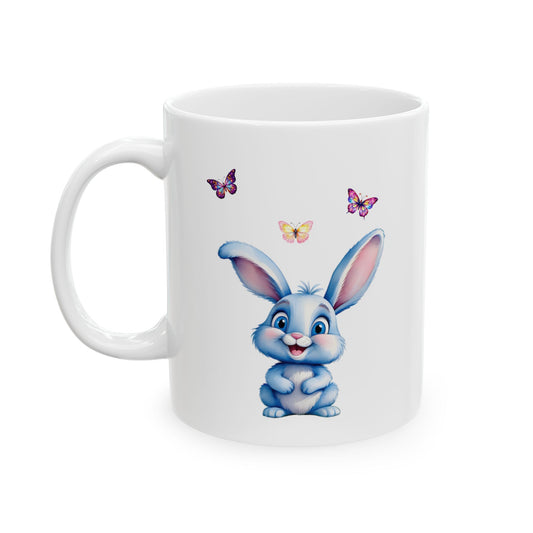 White ceramic coffee mug with a happy blue cartoon bunny sitting below three colorful butterflies.

