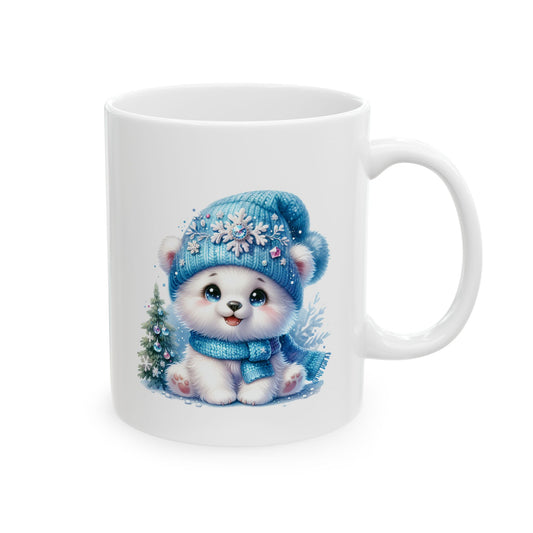 White ceramic coffee mug printed with an illustration of a cute white polar bear cub in a blue snowflake beanie sitting beside a small decorated Christmas tree