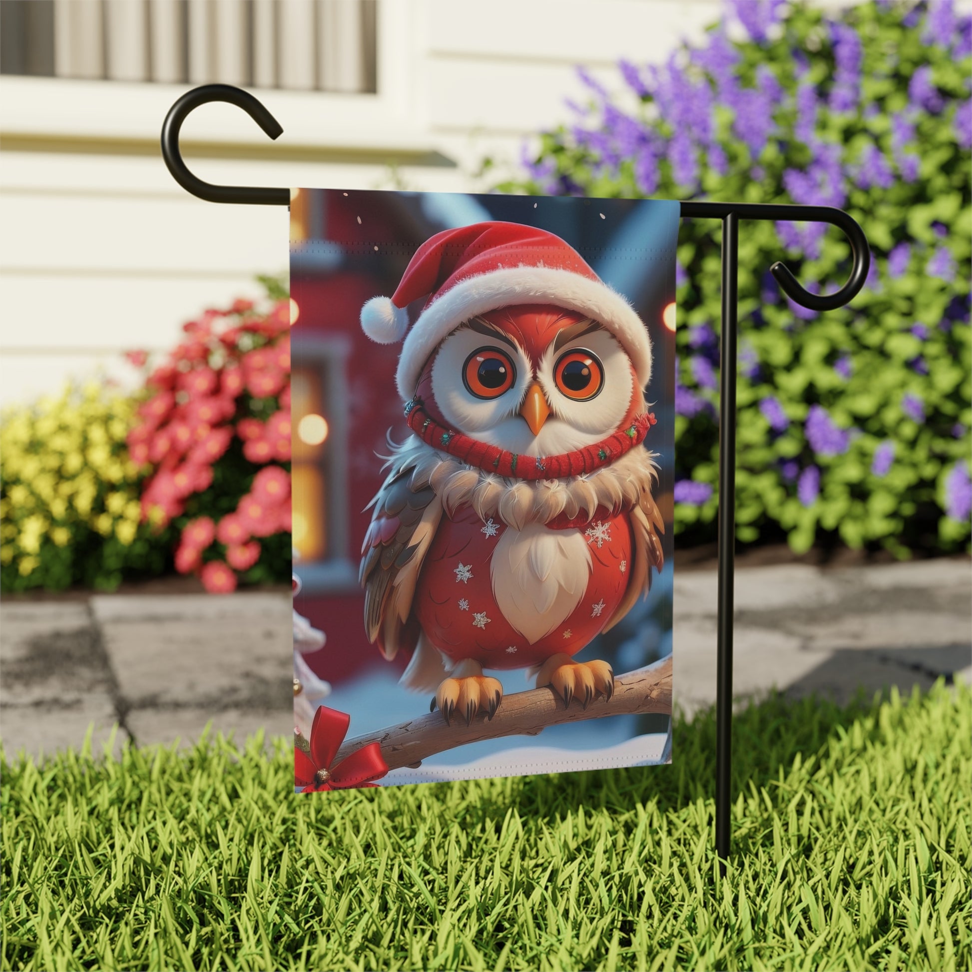 Garden flag with a cute cartoon owl wearing a red Santa hat and a red Christmas sweater, sitting on a snowy branch with blurred festive lights in the background.

