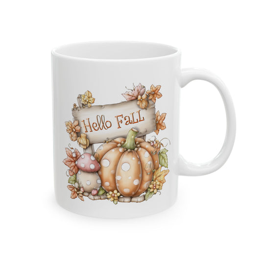 White ceramic coffee mug featuring a whimsical illustration of an orange polka-dot pumpkin and woodland mushrooms next to a wooden sign that reads Hello Fall.
