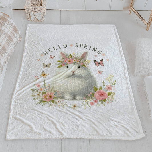 A soft "Hello Spring" velveteen blanket featuring a watercolor illustration of a fluffy white bunny with a flower crown and butterflies.